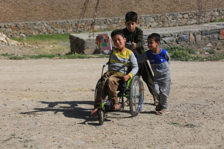 children pushing a child on a wheelchair